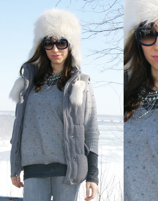 Woman standing in front on niagara falls with fluffy hat and grey outfit.