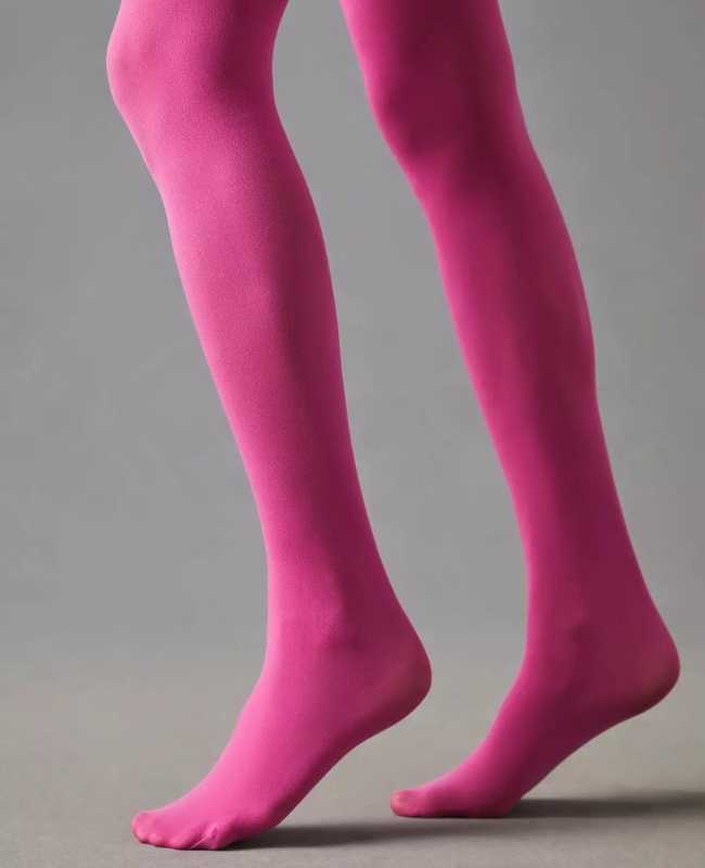 Close up of woman's legs wearing hot pink opaque stockings on grey background.