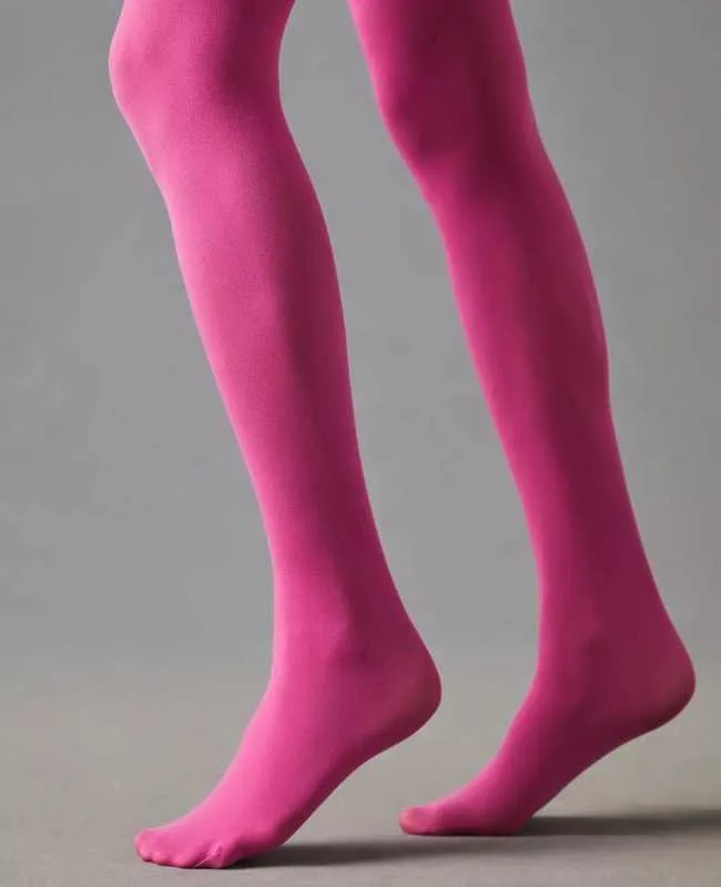 Close up of woman's legs wearing hot pink opaque stockings on grey background.