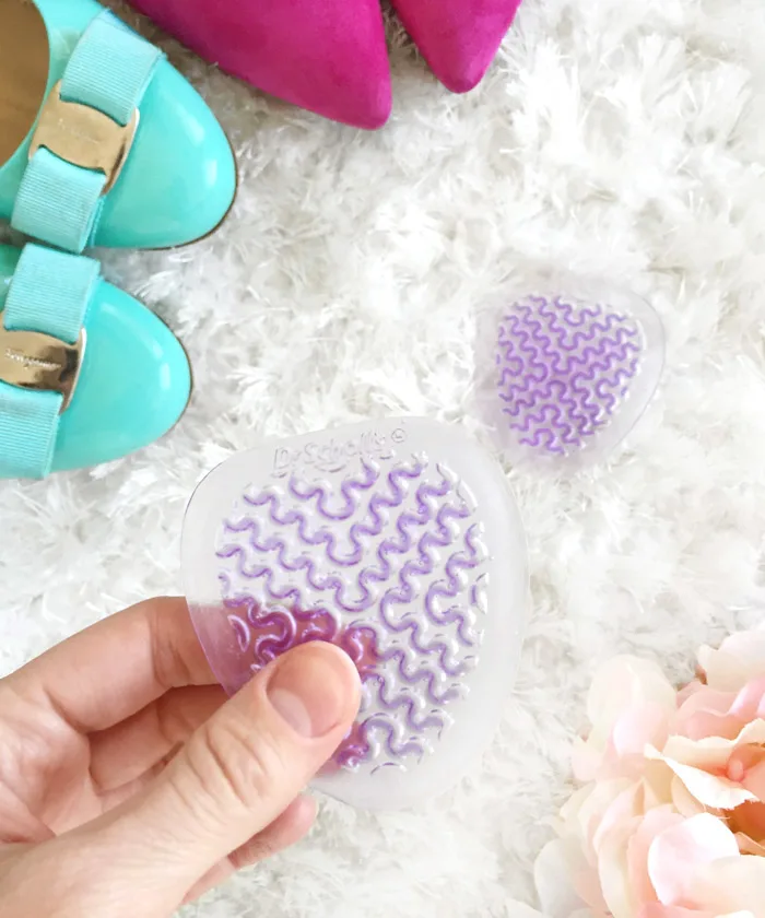 Woman holding shoe insole to keep heels from slipping out of shoes.