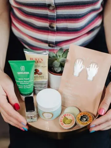Close up of woman's hands holding tray filled with moisturizing hand creams and products to cure dry hands and feet.