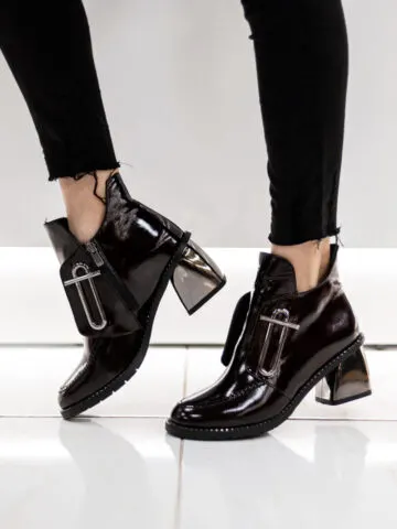 Closeup of women's legs in squeaky shoes in black patent leather on tile floor. Illustrating post on how to stop shoes from squeaking.