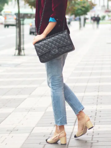 What shoes to wear with straight leg jeans with Side view of woman in jeans and jacket on street with bag.