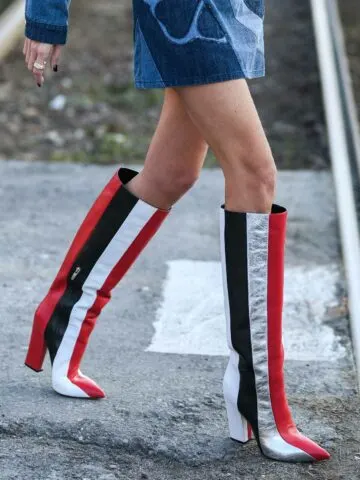 Cropped view of woman wearing type of boots called knee boots in striped red white and black.