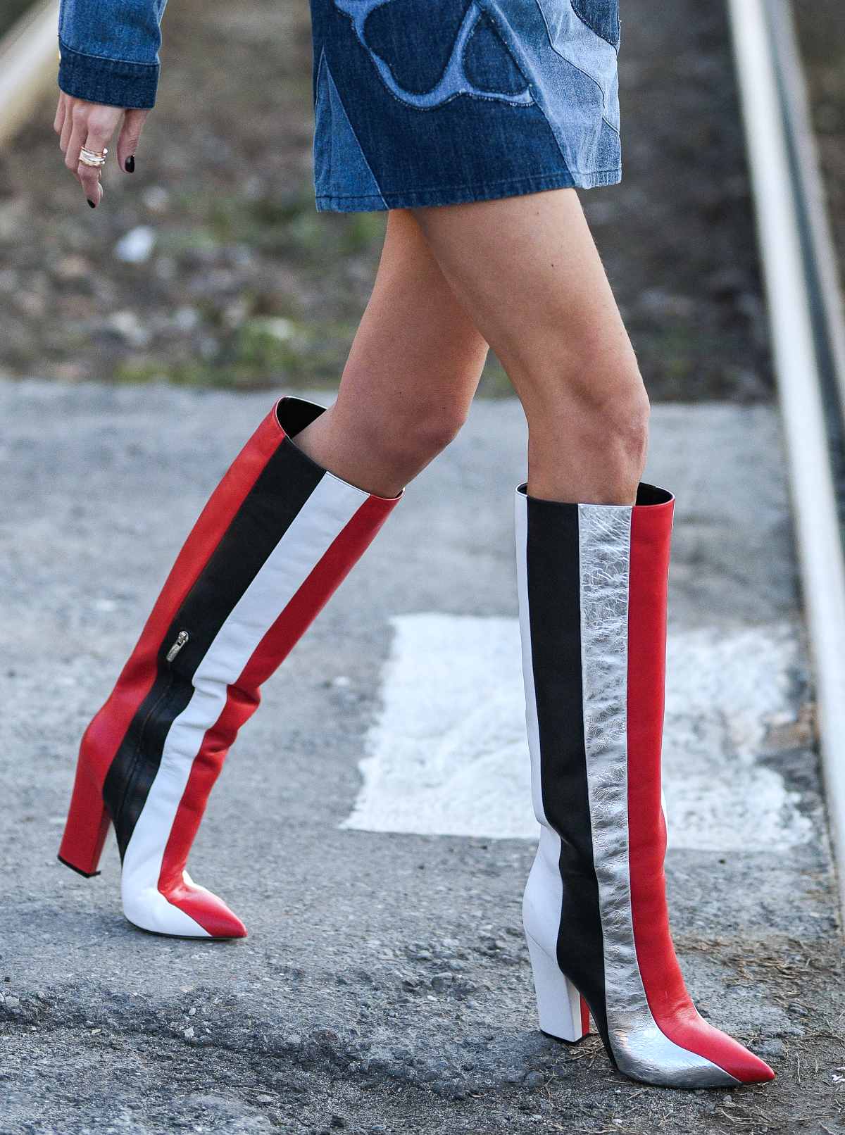 Cropped view of woman wearing type of boots called knee boots in striped red white and black.