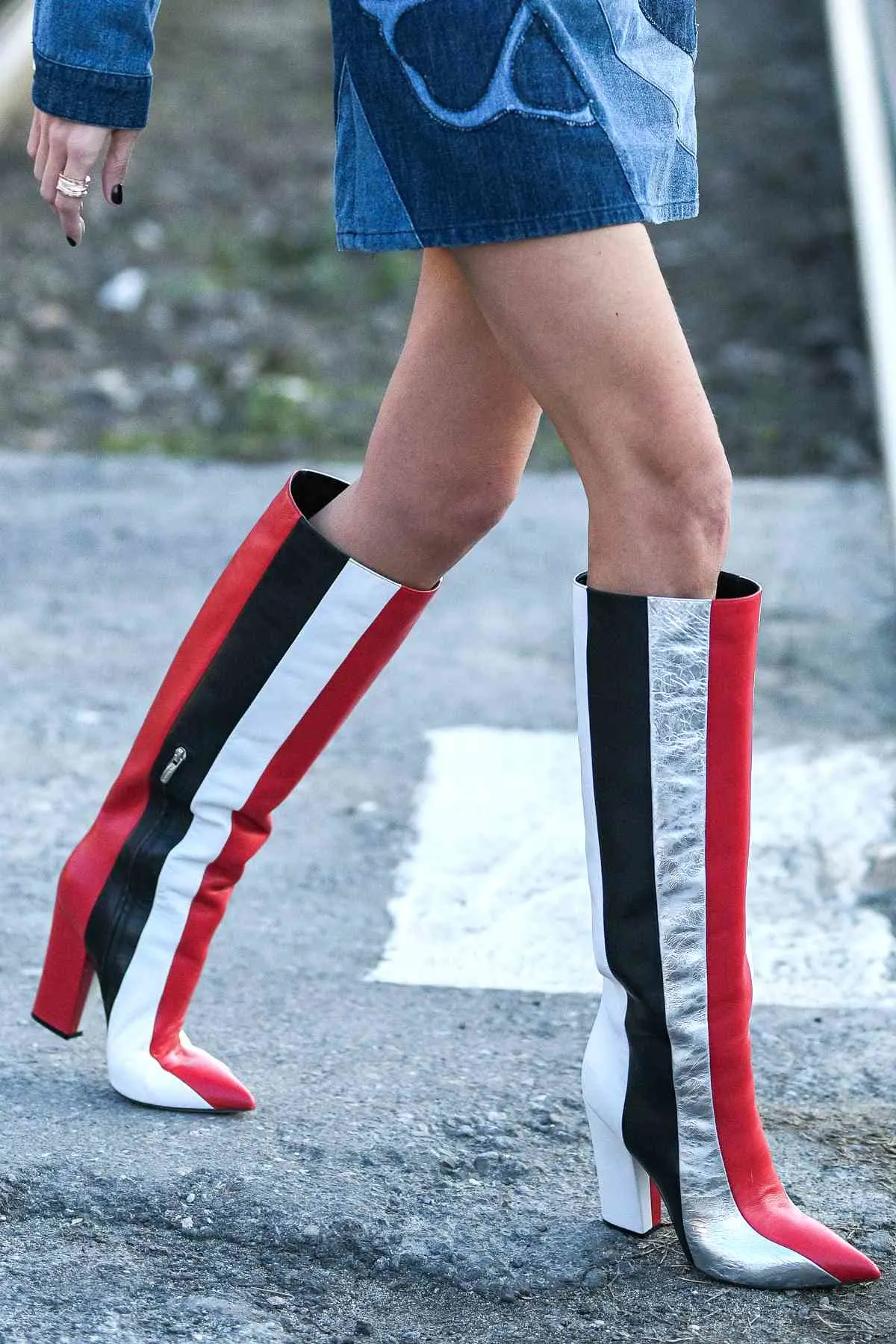 Cropped view of woman wearing type of boots called knee boots in striped red white and black.