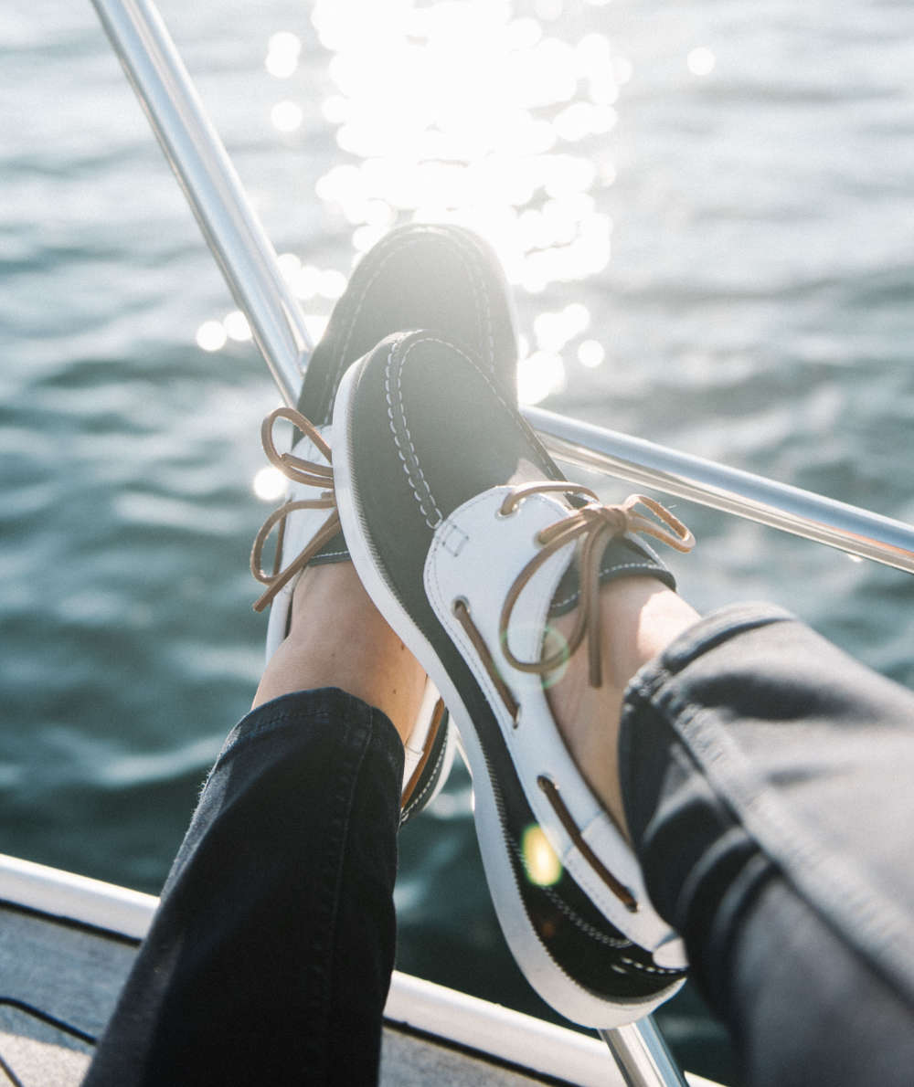 Close up of woman wearing boat shoes and black pants on sailboat.
