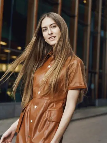 While woman with long hair wearing a brown dress made of leather.