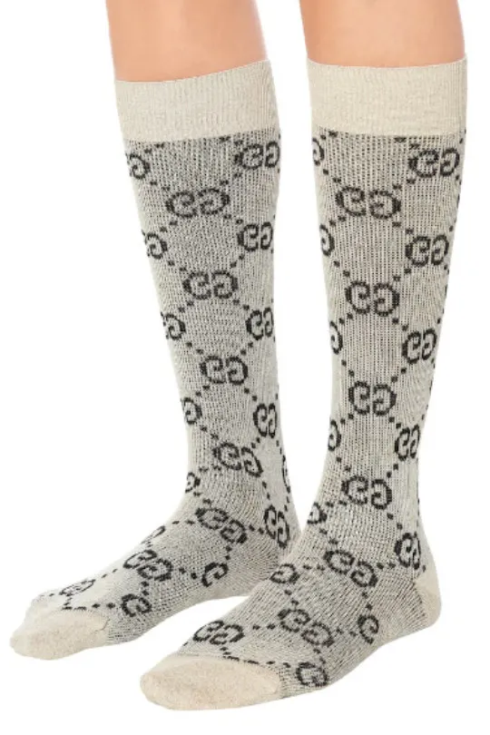 Close up of woman's legs wearing monogrammed Gucci socks in black white and beige.