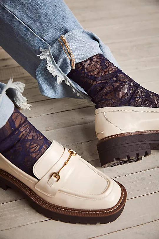 Close up of woman's feet wearing lace socks with loafers and cuffed jeans.