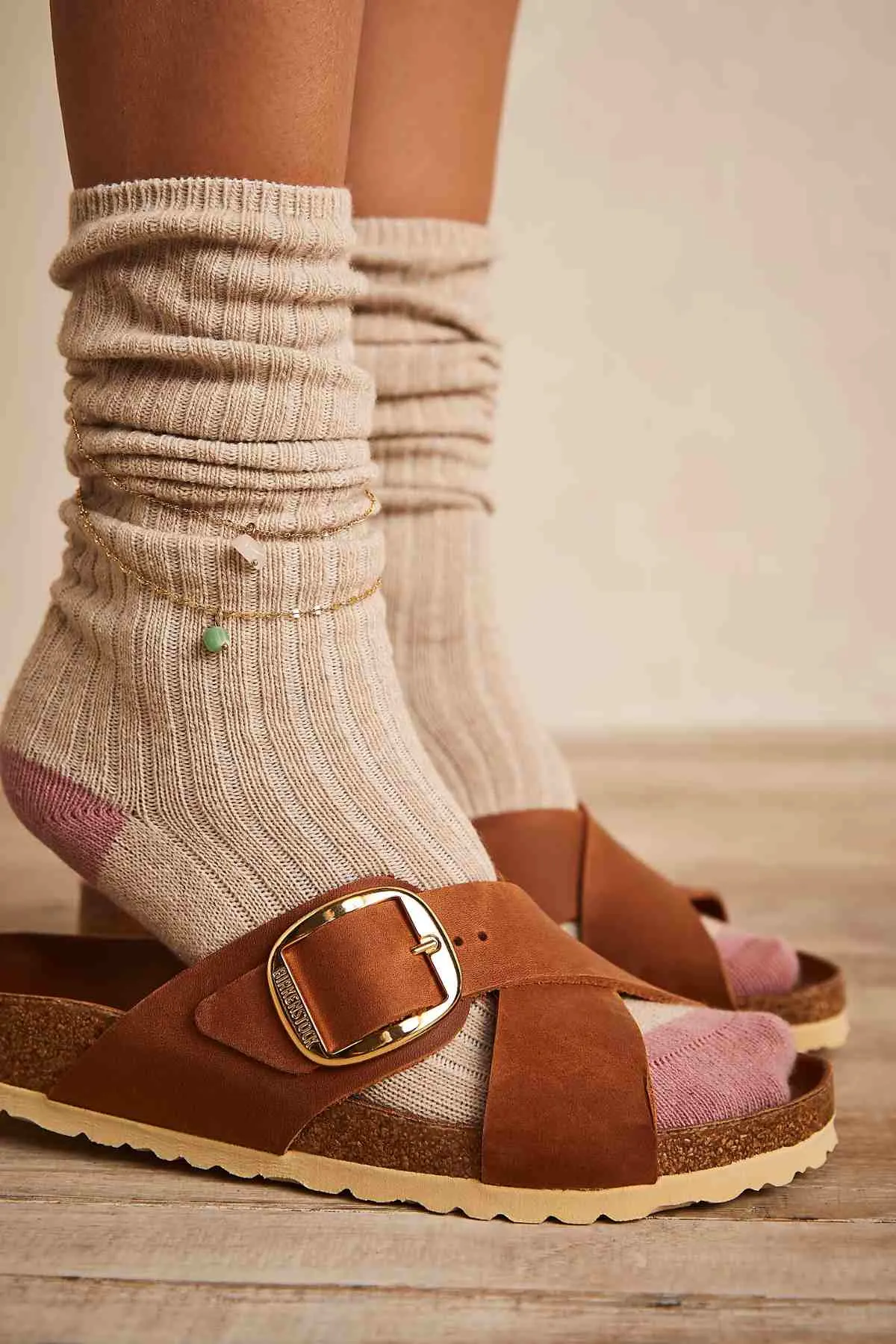 Cropped view of woman's feet wearing criss coss brown birkenstocks with socks in beige color.