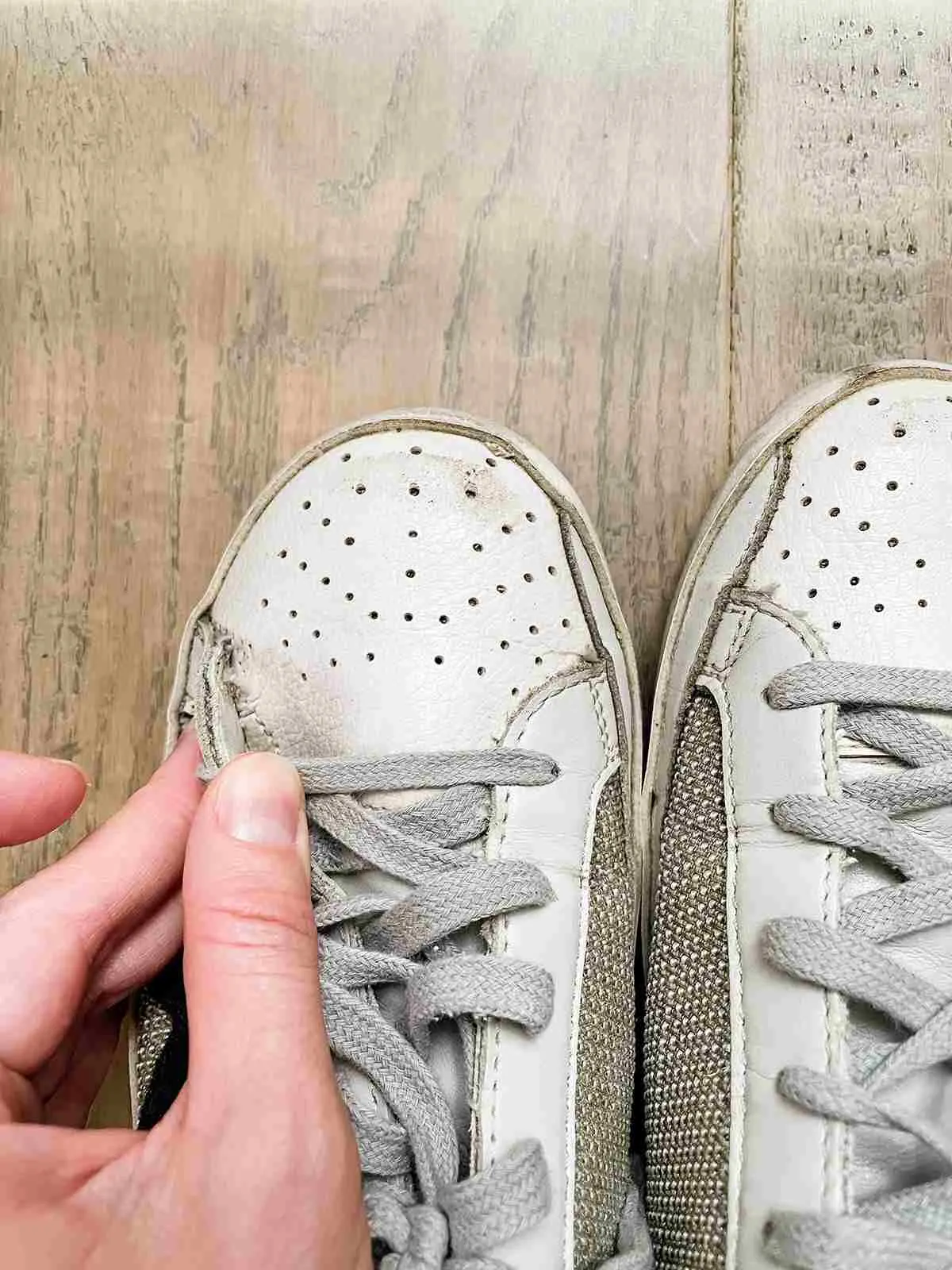 Close up top view of off-white Golden goose sneakers with woman sowing seam wear.