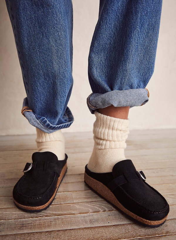 Close up of woman's feet wearing black Birkenstock clogs with wooly socks.