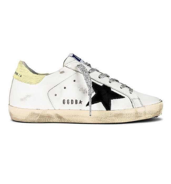 One white Golden Goose super star sneakers with black star sneakers on white background.
