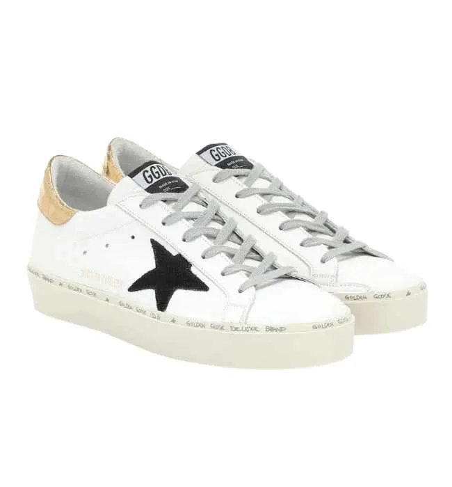 A pair of white Golden Goose Hi star sneakers with black star on white background.