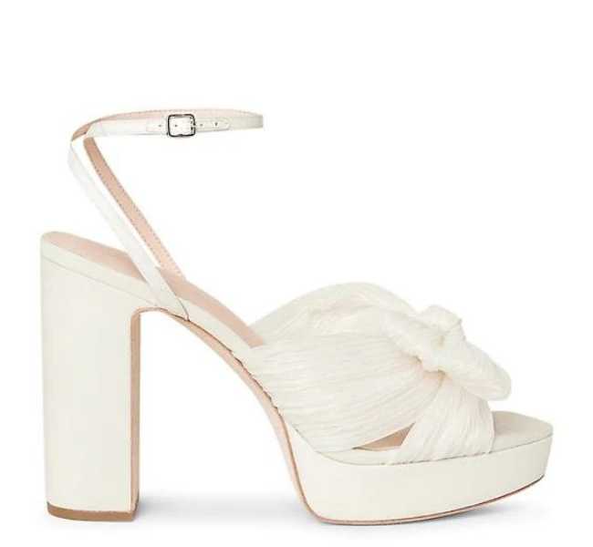 Cream colored platform wedding heel with fabric upper on white background.