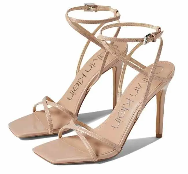 Beige patent leather strappy stiletto sandals on white background.