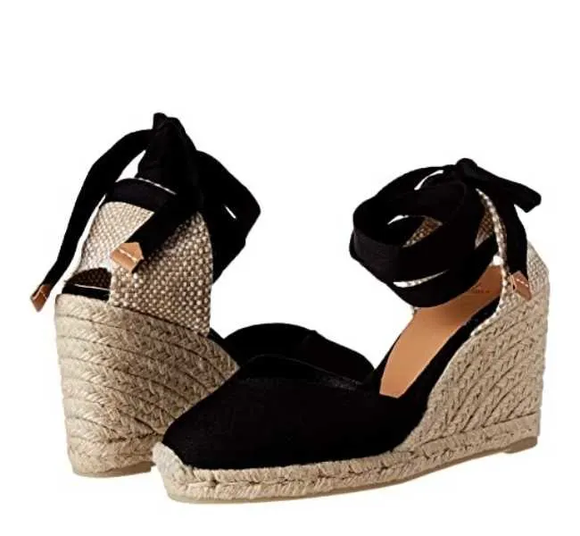 Black lace up round toe espadrille wedge heels on white background.