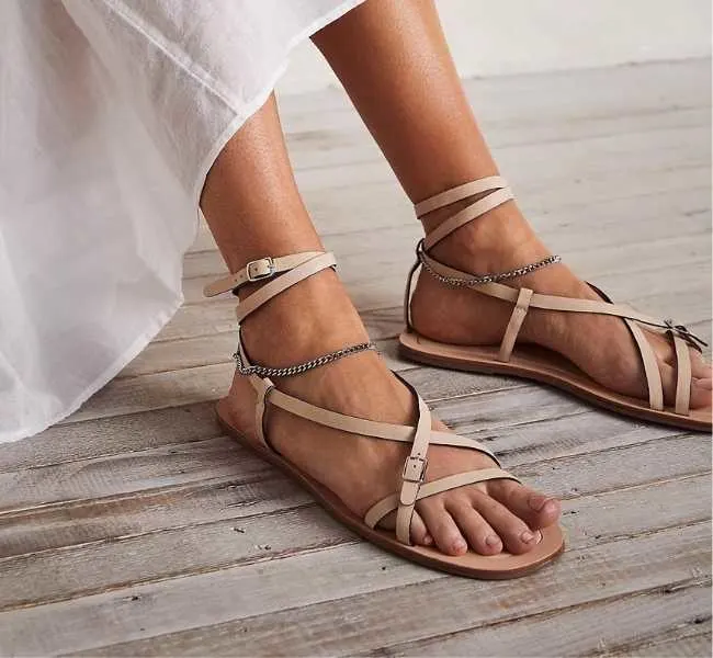 Beige slip on strappy sandals on white background.
