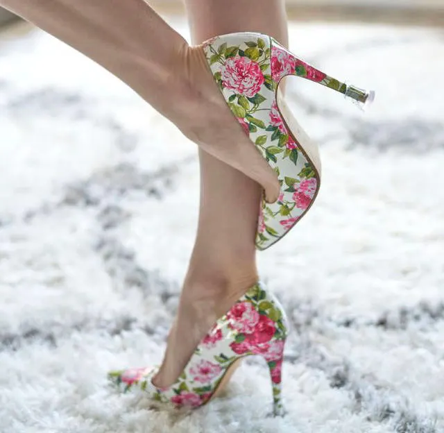Close up image of women wearing a pair of floral print heels standing on a white rug on ShoeTease shoe blog website.