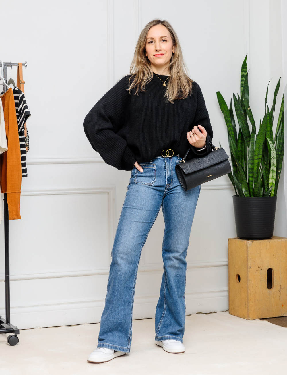 Woman wearing flare jeans with white sneakers outfit for fall/winter.