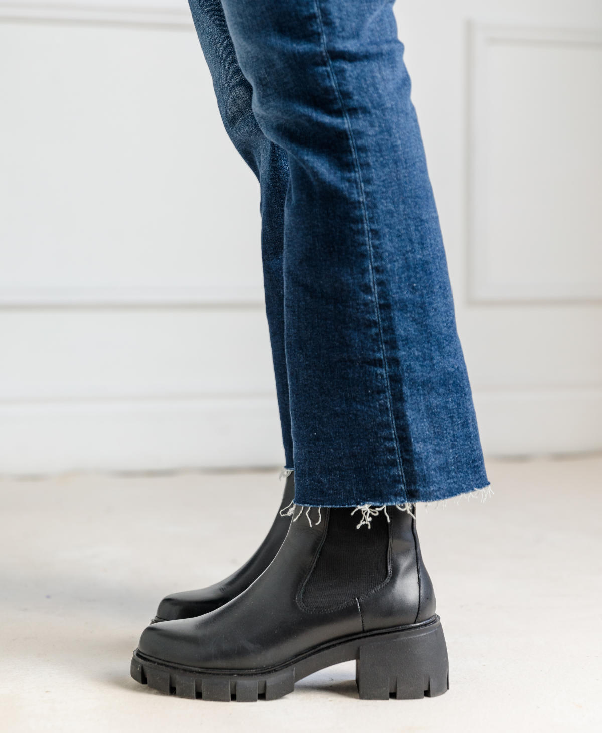 Close of up woman wearing blue cropped flared jeans with black Chelsea boots.