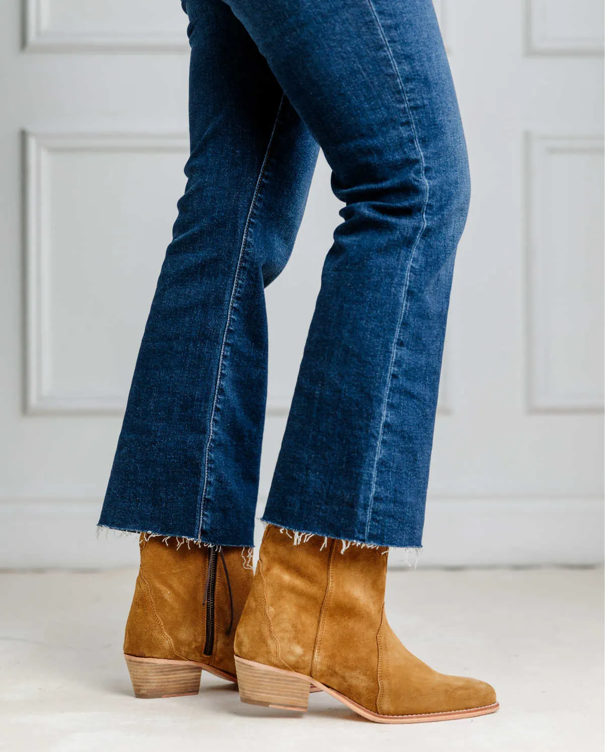Cropped view of woman's legs wearing kick flares and western boots.