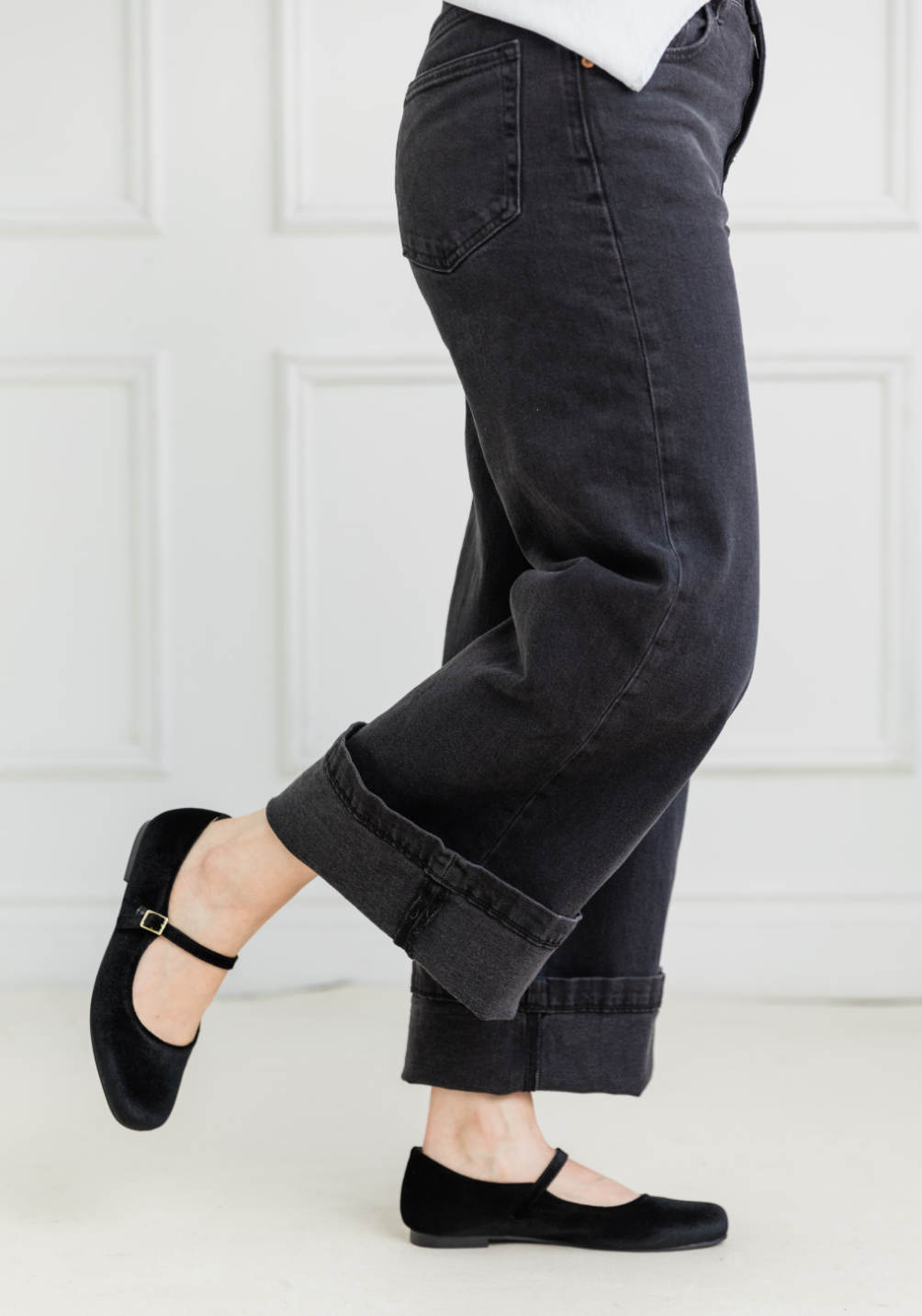 Cropped view of woman wearing cuffed wide leg jeans with ballerina flats.