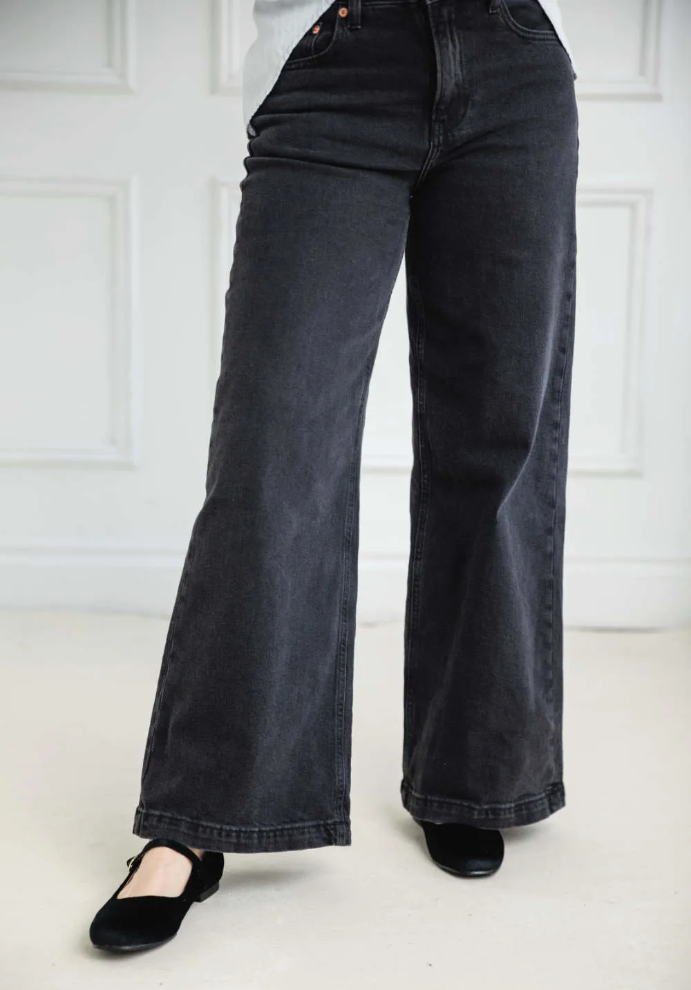 Cropped view of woman wearing full length wide leg jeans with ballerina flats.